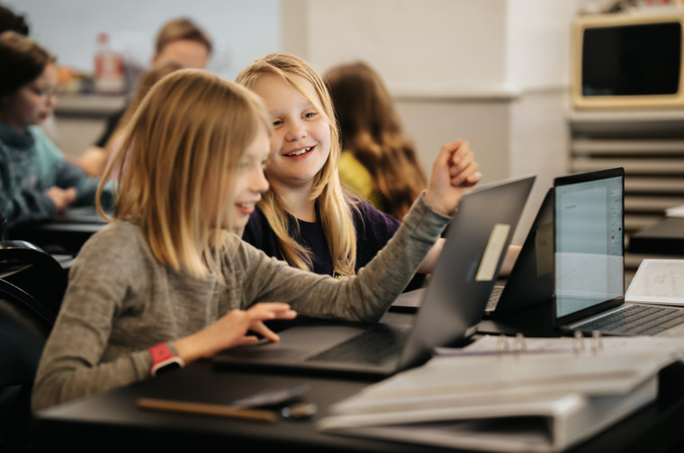 Children in writing class sitting in front of computers.