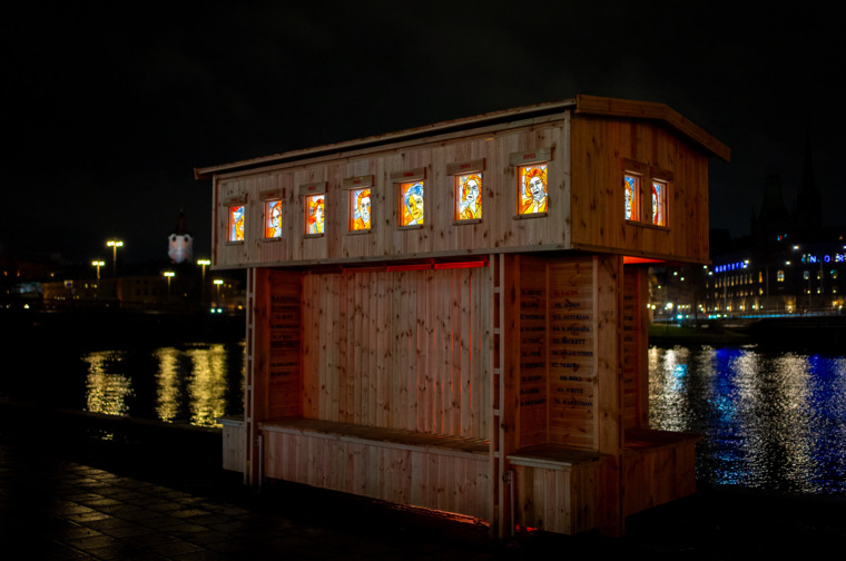 Image showing a wooden construction with illuminated colroful windows. It's the artwork De Aderton from Nobel Week Lighst 2024.
