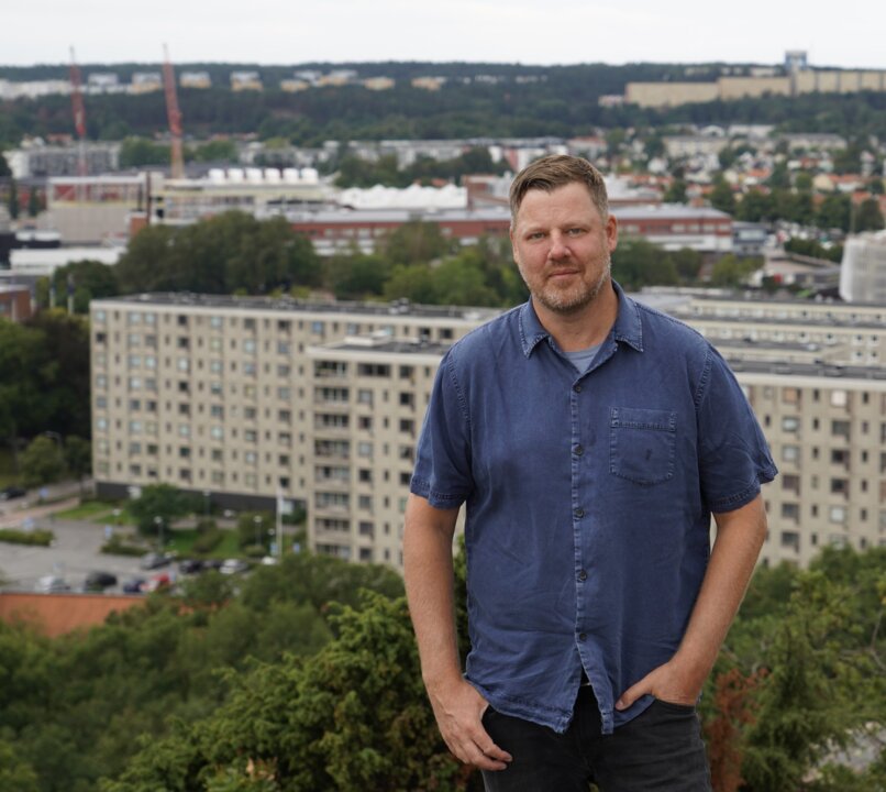 Bild på man som står uppe på en höjd, med en stad i bakgrunden